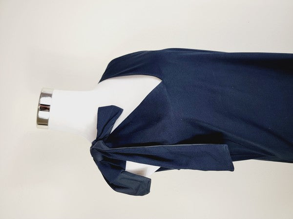 A mannequin displays a Cotton Jersey dress in navy blue with side pockets, featuring a sleeveless design and a large bow on the left shoulder.