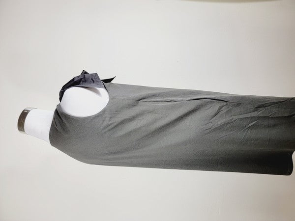 A Cotton Jersey dress in dark grey Turkish cotton, displayed on a mannequin, featuring an adjustable tie shoulder with a large bow on the left side and pockets, set against a plain white background.