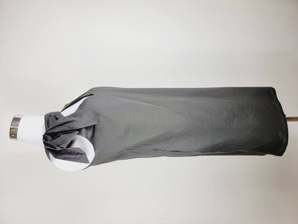 A Cotton Jersey dress in dark grey Turkish cotton, displayed on a mannequin, featuring an adjustable tie shoulder with a large bow on the left side and pockets, set against a plain white background.