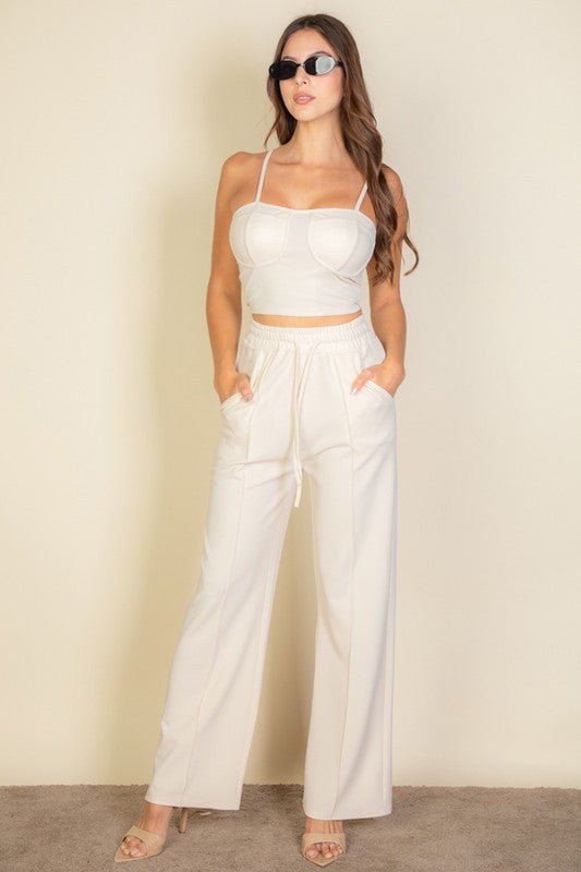 Sporting the Bustier Cami Top & Slant Straight Pants, a person poses against a light-colored background, accessorized with sunglasses and open-toed shoes.