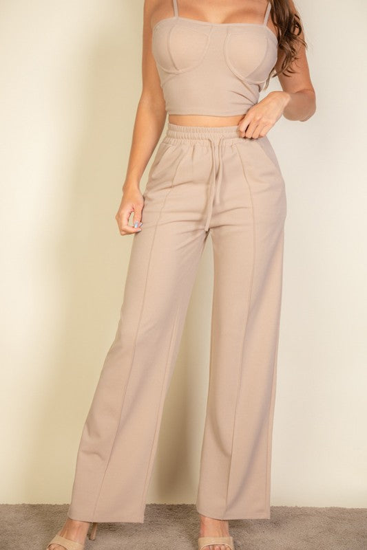 Sporting the Bustier Cami Top & Slant Straight Pants, a person poses against a light-colored background, accessorized with sunglasses and open-toed shoes.