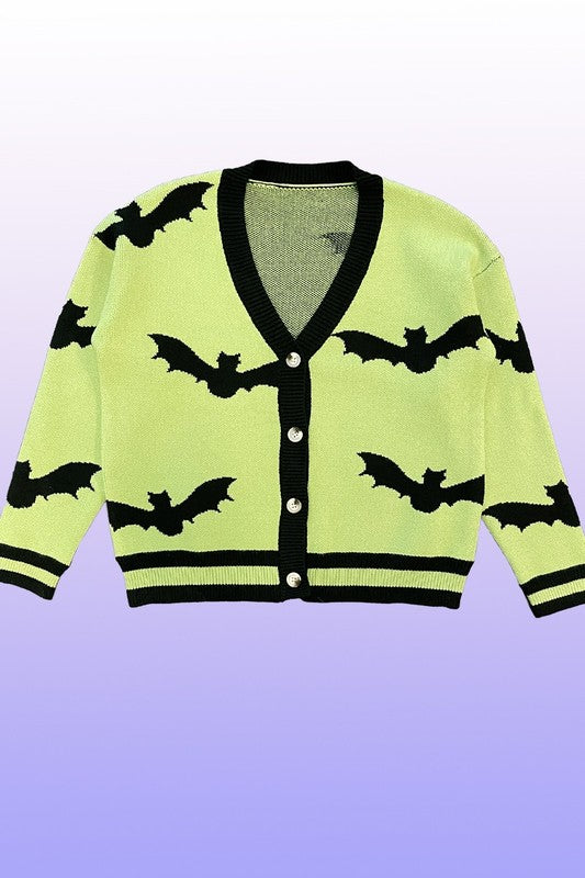 An exclusive in-house design, the PLUS SIZE Halloween knit cardigan features black bat intarsia patterns, black trim, and a black button closure on a lime green background. Set against a gradient backdrop transitioning from light purple at the top to blue at the bottom, this piece offers added comfort and style for plus sizes.