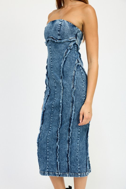 A person wearing the TUBE FRAYED SEAM MIDI DRESS, a strapless, form-fitting denim dress with frayed edges, and imported black ankle boots poses against a plain white background.