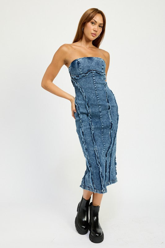 A person wearing the TUBE FRAYED SEAM MIDI DRESS, a strapless, form-fitting denim dress with frayed edges, and imported black ankle boots poses against a plain white background.