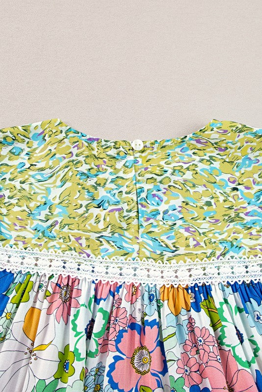 A short-sleeved tunic with bubble sleeves, featuring a lace panel on the chest and a retro pattern of green, blue, pink, and orange flowers on a white background.