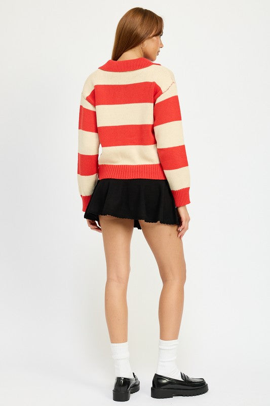 A person with long hair is wearing the STRIPED COLLARED SWEATER TOP, featuring red and white stripes with buttons, paired with a black skirt. The model wears size small, showcasing the piece’s sleek fit against a plain white background.