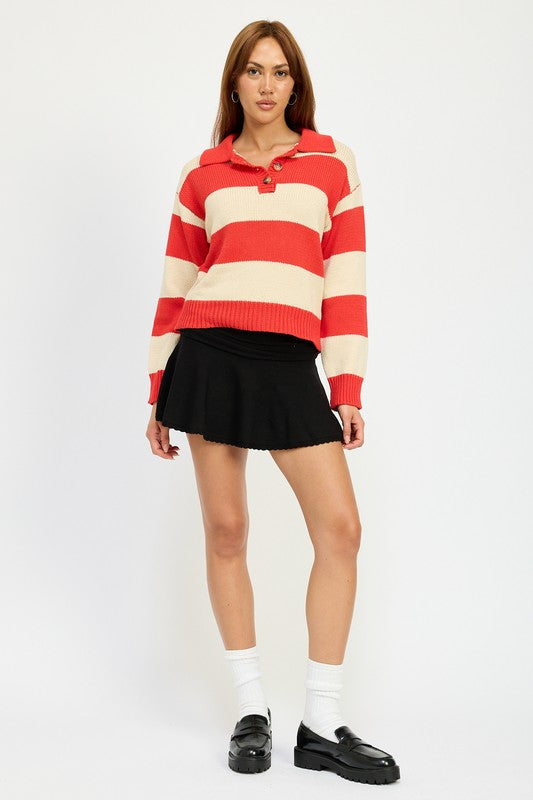 A person with long hair is wearing the STRIPED COLLARED SWEATER TOP, featuring red and white stripes with buttons, paired with a black skirt. The model wears size small, showcasing the piece’s sleek fit against a plain white background.