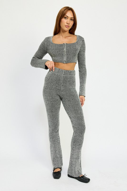 A person wearing HIGH WAIST RIBED PANTS and a grey knit long-sleeve crop top, made from 60% cotton, size small, standing against a plain background.