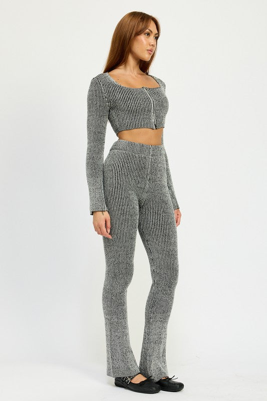 A person wearing HIGH WAIST RIBED PANTS and a grey knit long-sleeve crop top, made from 60% cotton, size small, standing against a plain background.