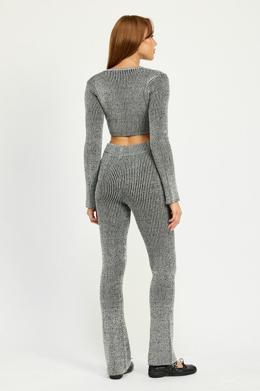 A person wearing HIGH WAIST RIBED PANTS and a grey knit long-sleeve crop top, made from 60% cotton, size small, standing against a plain background.