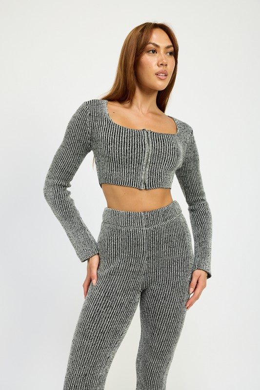 A person wearing HIGH WAIST RIBED PANTS and a grey knit long-sleeve crop top, made from 60% cotton, size small, standing against a plain background.