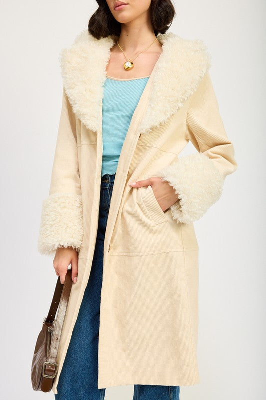 A woman in a blue top, jeans, and sneakers, wearing the FAUX FUR MID TRENCH COAT in beige with white fur trim on the collar and cuffs, size small, stands against a plain background.