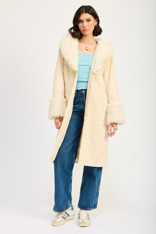 A woman in a blue top, jeans, and sneakers, wearing the FAUX FUR MID TRENCH COAT in beige with white fur trim on the collar and cuffs, size small, stands against a plain background.