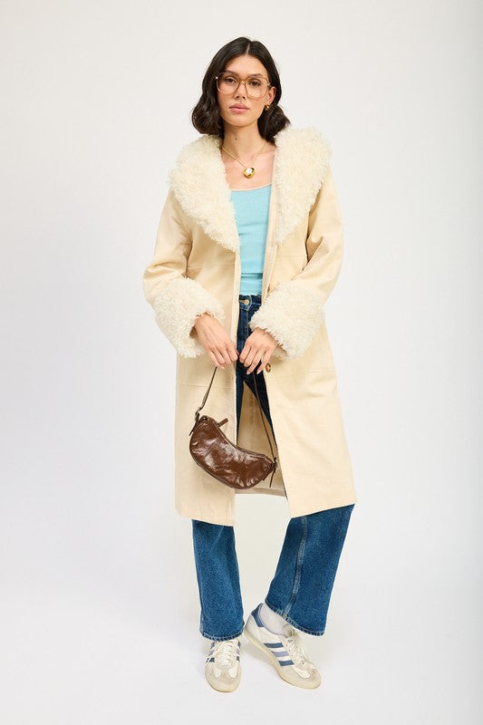 A woman in a blue top, jeans, and sneakers, wearing the FAUX FUR MID TRENCH COAT in beige with white fur trim on the collar and cuffs, size small, stands against a plain background.