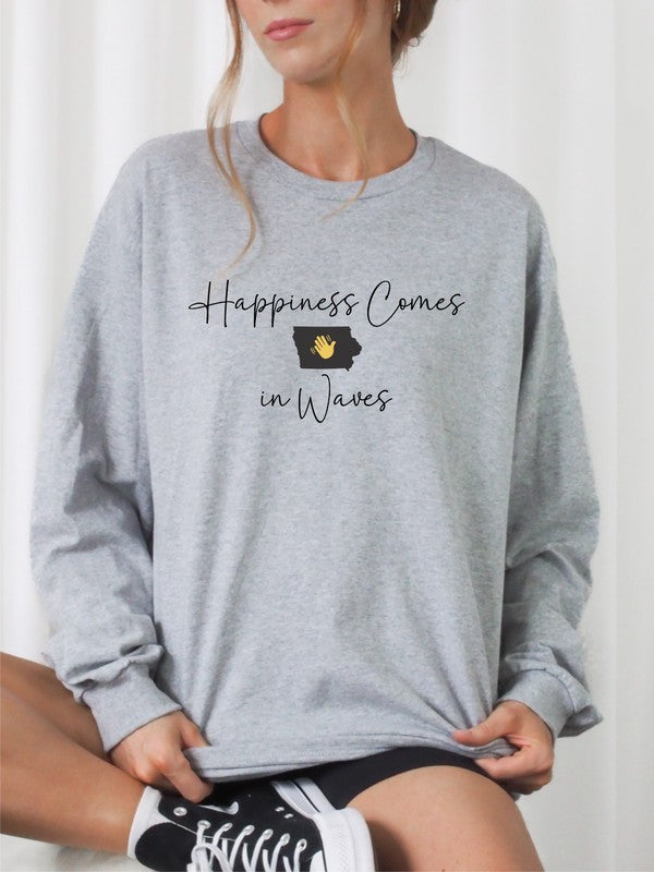 A person wearing the "Happiness Comes in Waves Cozy Sweatshirt," which features an illustration of a wave and a sun along with the text, effortlessly combines comfort and style. The unisex garment pairs perfectly with the person's long hair and orange-painted nails.