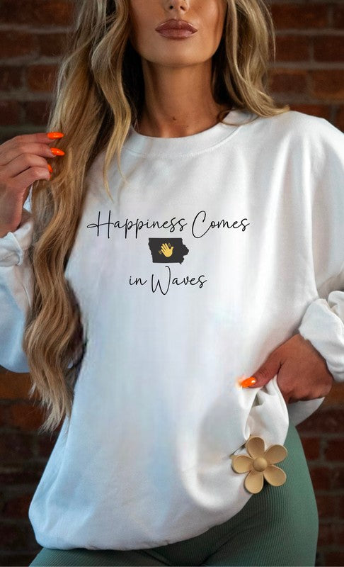 A person wearing the "Happiness Comes in Waves Cozy Sweatshirt," which features an illustration of a wave and a sun along with the text, effortlessly combines comfort and style. The unisex garment pairs perfectly with the person's long hair and orange-painted nails.