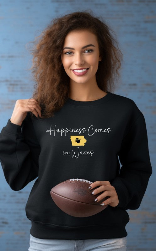 A person wearing the "Happiness Comes in Waves Cozy Sweatshirt," which features an illustration of a wave and a sun along with the text, effortlessly combines comfort and style. The unisex garment pairs perfectly with the person's long hair and orange-painted nails.