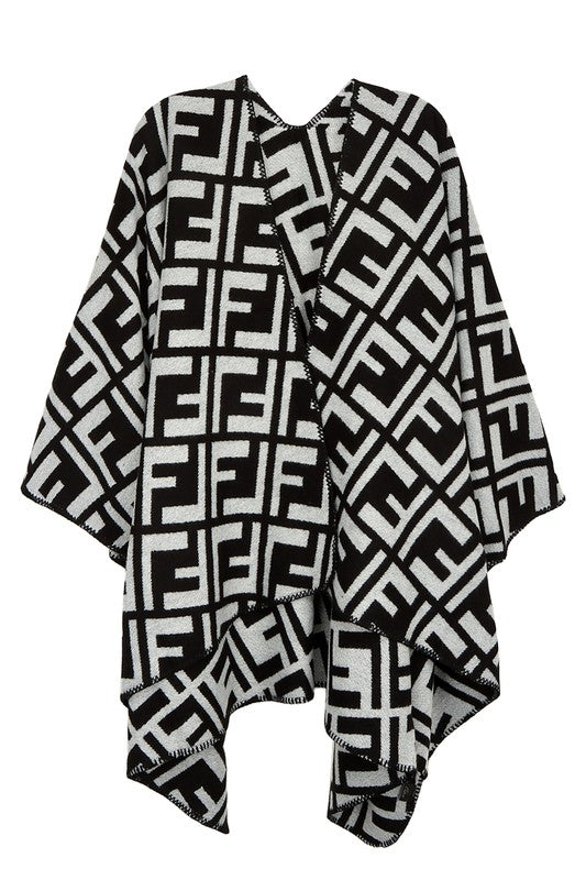 The Greek Pattern Poncho is a black and white poncho featuring an all-over geometric Greek pattern and an asymmetrical hem.