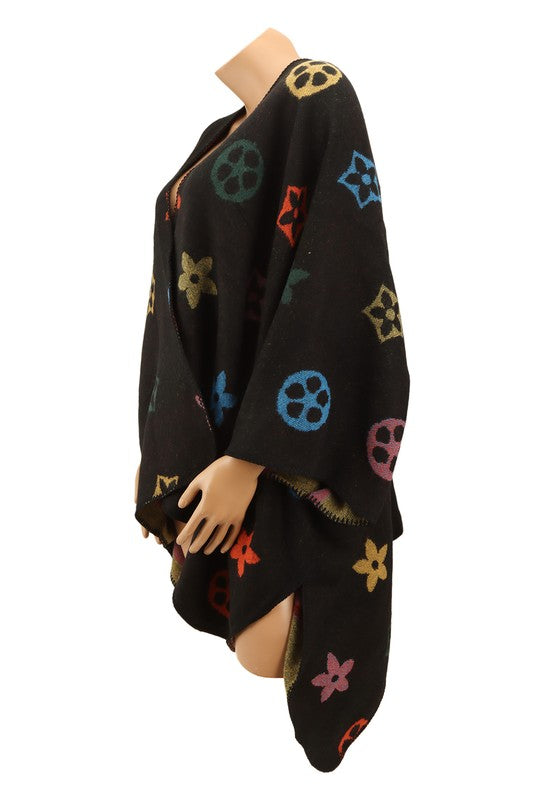 A black poncho featuring a colorful floral and geometric pattern. Styled open in the front with a draped design, this piece offers the elegance of the Multi Color and Geometric Pattern Poncho.