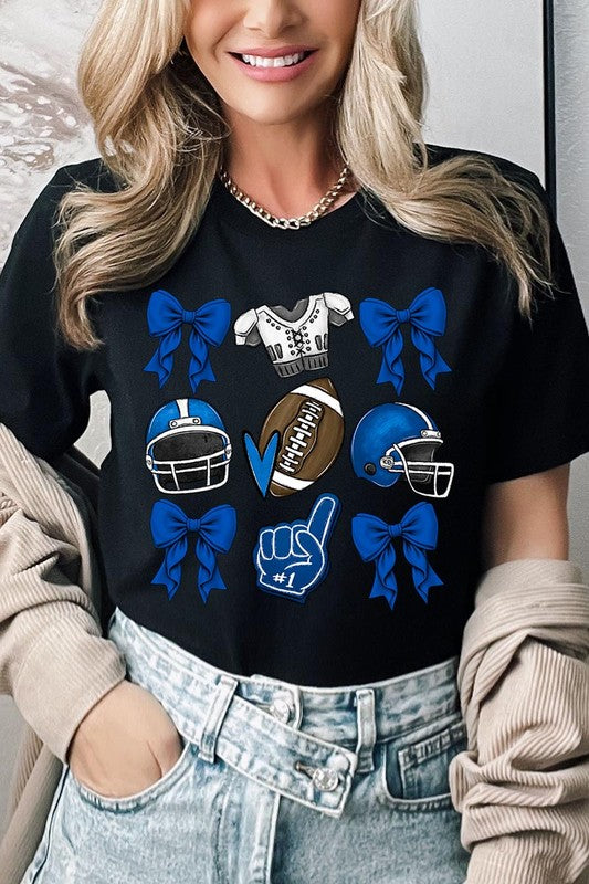 A woman wearing a Blue Coquette Football Graphic Tee adorned with blue bows, helmets, a football, a foam finger, and a jersey. She has yellow painted nails and is holding her shirt. This high-quality printed design guarantees long-lasting wear and vibrant colors.