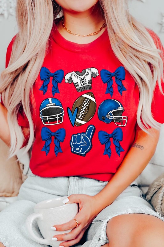 A woman wearing a Blue Coquette Football Graphic Tee adorned with blue bows, helmets, a football, a foam finger, and a jersey. She has yellow painted nails and is holding her shirt. This high-quality printed design guarantees long-lasting wear and vibrant colors.