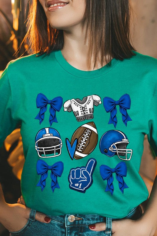 A woman wearing a Blue Coquette Football Graphic Tee adorned with blue bows, helmets, a football, a foam finger, and a jersey. She has yellow painted nails and is holding her shirt. This high-quality printed design guarantees long-lasting wear and vibrant colors.