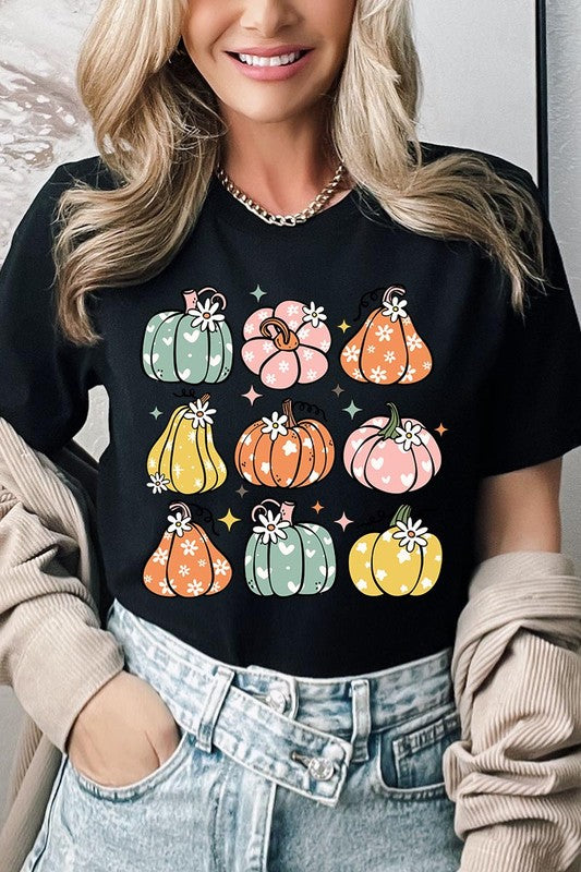 Person wearing a white Pumpkins & Daisies Retro Fall Graphic Tee featuring colorful, cartoonish pumpkins in various shapes and designs, beneath an open jean jacket.