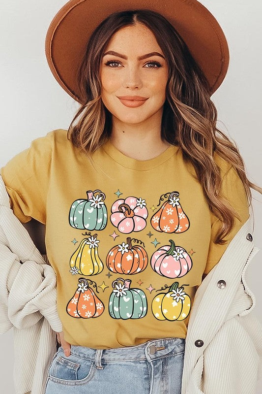 Person wearing a white Pumpkins & Daisies Retro Fall Graphic Tee featuring colorful, cartoonish pumpkins in various shapes and designs, beneath an open jean jacket.