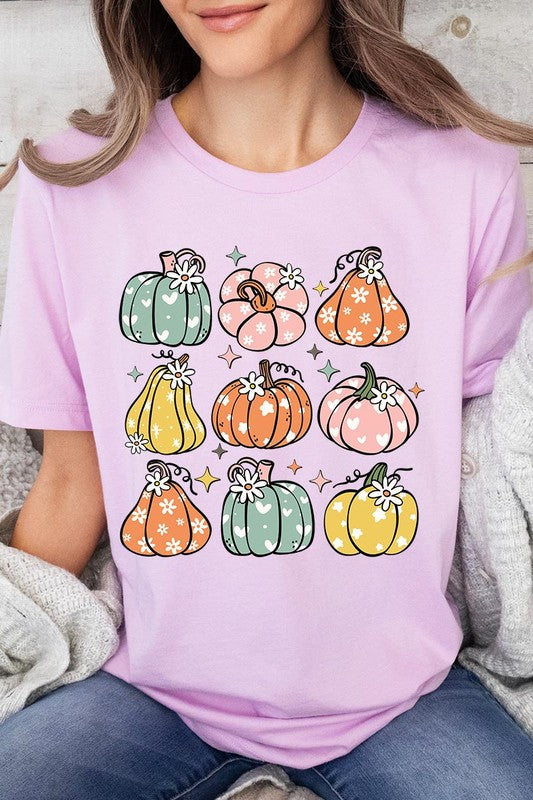 Person wearing a white Pumpkins & Daisies Retro Fall Graphic Tee featuring colorful, cartoonish pumpkins in various shapes and designs, beneath an open jean jacket.