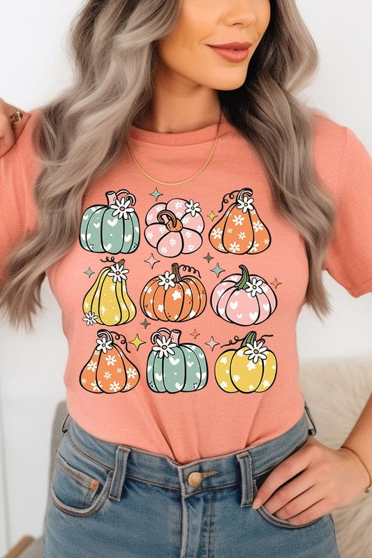 Person wearing a white Pumpkins & Daisies Retro Fall Graphic Tee featuring colorful, cartoonish pumpkins in various shapes and designs, beneath an open jean jacket.