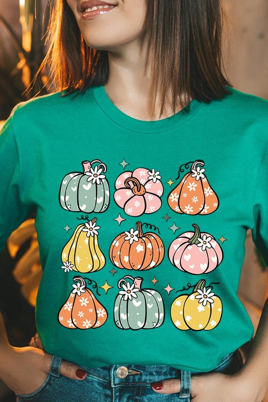 Person wearing a white Pumpkins & Daisies Retro Fall Graphic Tee featuring colorful, cartoonish pumpkins in various shapes and designs, beneath an open jean jacket.