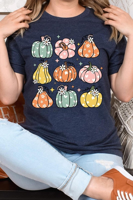 Person wearing a white Pumpkins & Daisies Retro Fall Graphic Tee featuring colorful, cartoonish pumpkins in various shapes and designs, beneath an open jean jacket.