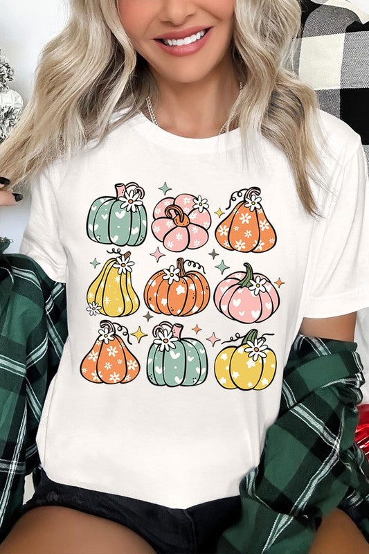 Person wearing a white Pumpkins & Daisies Retro Fall Graphic Tee featuring colorful, cartoonish pumpkins in various shapes and designs, beneath an open jean jacket.