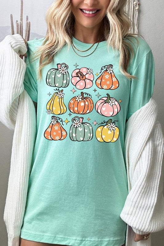 Person wearing a white Pumpkins & Daisies Retro Fall Graphic Tee featuring colorful, cartoonish pumpkins in various shapes and designs, beneath an open jean jacket.