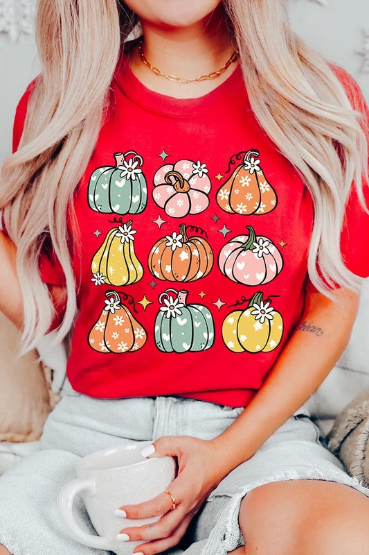 Person wearing a white Pumpkins & Daisies Retro Fall Graphic Tee featuring colorful, cartoonish pumpkins in various shapes and designs, beneath an open jean jacket.