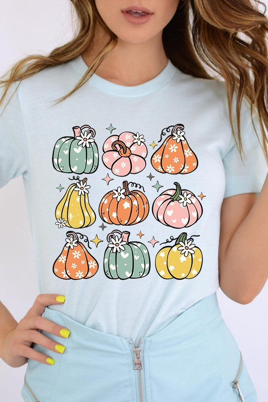 Person wearing a white Pumpkins & Daisies Retro Fall Graphic Tee featuring colorful, cartoonish pumpkins in various shapes and designs, beneath an open jean jacket.