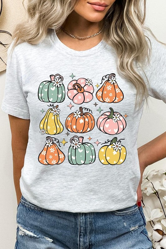 Person wearing a white Pumpkins & Daisies Retro Fall Graphic Tee featuring colorful, cartoonish pumpkins in various shapes and designs, beneath an open jean jacket.