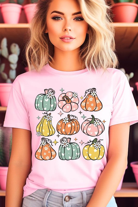 Person wearing a white Pumpkins & Daisies Retro Fall Graphic Tee featuring colorful, cartoonish pumpkins in various shapes and designs, beneath an open jean jacket.