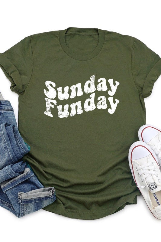 The "Sunday Funday" graphic tee with high-quality direct-to-film printing is paired with light blue distressed denim shorts, a brown hat, and a woven bag on a wooden hanger rack.