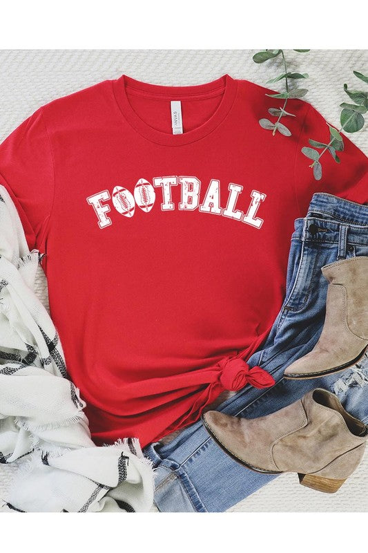 The Football Graphic Tee in beige features "FOOTBALL" in black lettering, paired with light blue distressed denim shorts and a pair of sunglasses. Crafted from premium materials for maximum comfort and style, this unisex crew neck short sleeve shirt is perfect for casual outings.