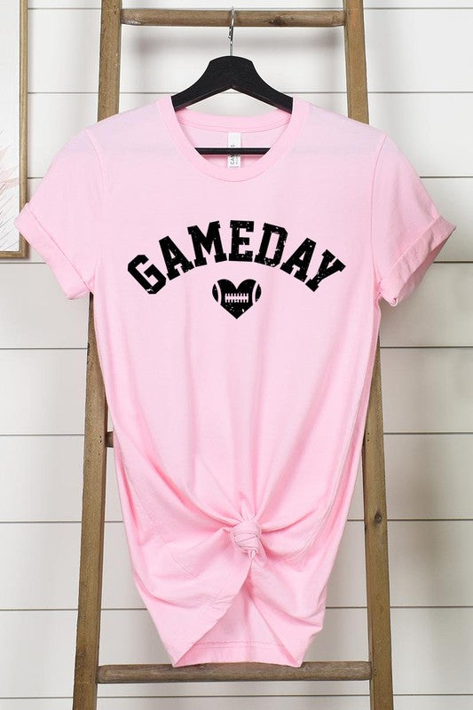 A red Game Day Football Heart Graphic Tee featuring the word "GAMEDAY" with a football inside a heart graphic below it, laid on a white surface paired with blue jeans, a striped scarf, and tan ankle boots. Ideal for Family Group Uniforms on game day!