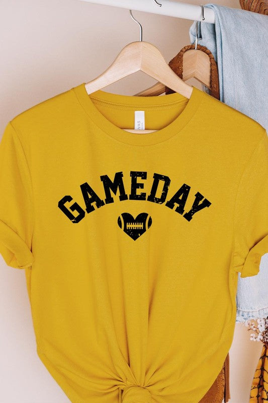 A red Game Day Football Heart Graphic Tee featuring the word "GAMEDAY" with a football inside a heart graphic below it, laid on a white surface paired with blue jeans, a striped scarf, and tan ankle boots. Ideal for Family Group Uniforms on game day!