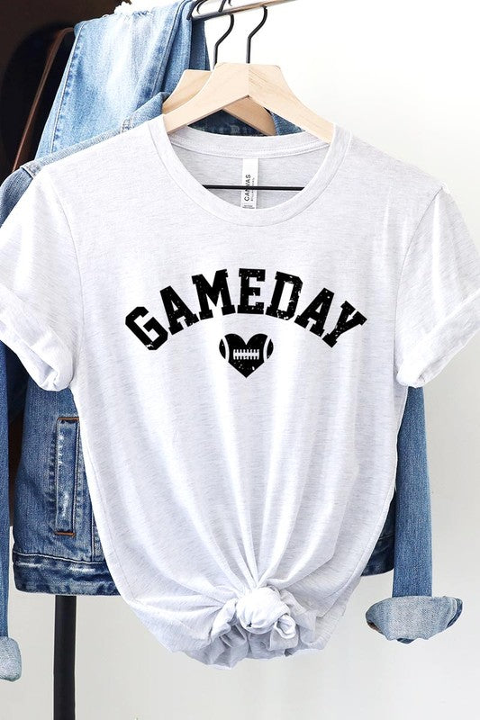 A red Game Day Football Heart Graphic Tee featuring the word "GAMEDAY" with a football inside a heart graphic below it, laid on a white surface paired with blue jeans, a striped scarf, and tan ankle boots. Ideal for Family Group Uniforms on game day!