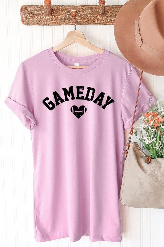 A red Game Day Football Heart Graphic Tee featuring the word "GAMEDAY" with a football inside a heart graphic below it, laid on a white surface paired with blue jeans, a striped scarf, and tan ankle boots. Ideal for Family Group Uniforms on game day!