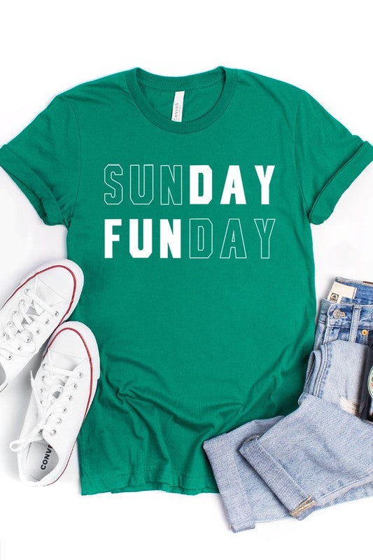 A light pink Sunday Funday Graphic Tee featuring the "SUNDAY FUNDAY" print is hanging on a wooden hanger next to a tan hat and a beige bag filled with flowers. This unisex crew neck short sleeve tee is ideal for family group uniforms.