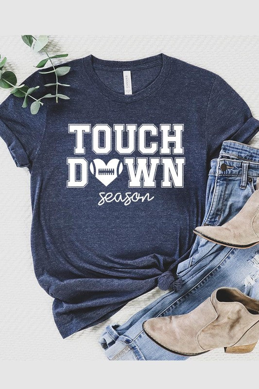 A Touchdown Season Graphic Tee in dark gray with a high-quality direct-to-film printed design, paired with blue jeans and beige ankle boots, laid out flat.