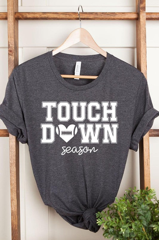 A Touchdown Season Graphic Tee in dark gray with a high-quality direct-to-film printed design, paired with blue jeans and beige ankle boots, laid out flat.