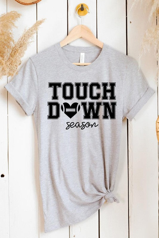 A Touchdown Season Graphic Tee in dark gray with a high-quality direct-to-film printed design, paired with blue jeans and beige ankle boots, laid out flat.