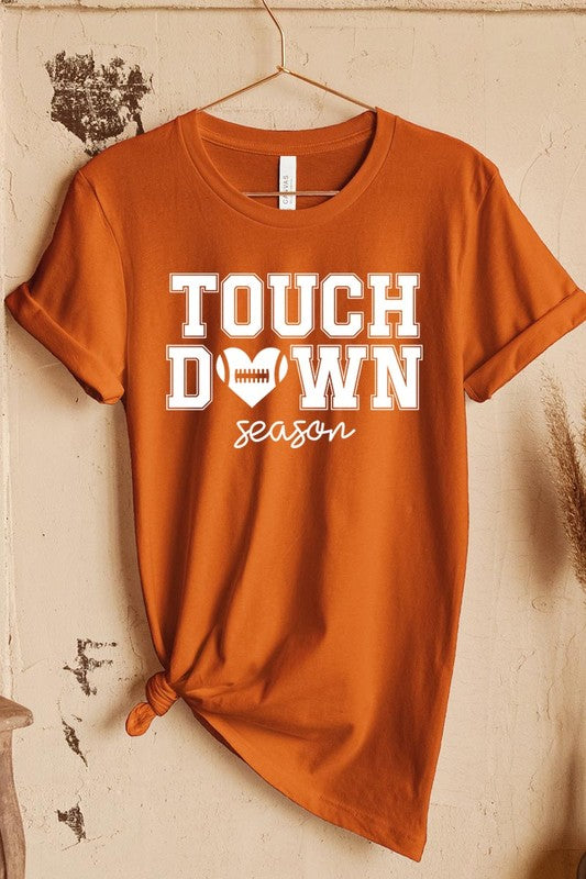 A Touchdown Season Graphic Tee in dark gray with a high-quality direct-to-film printed design, paired with blue jeans and beige ankle boots, laid out flat.