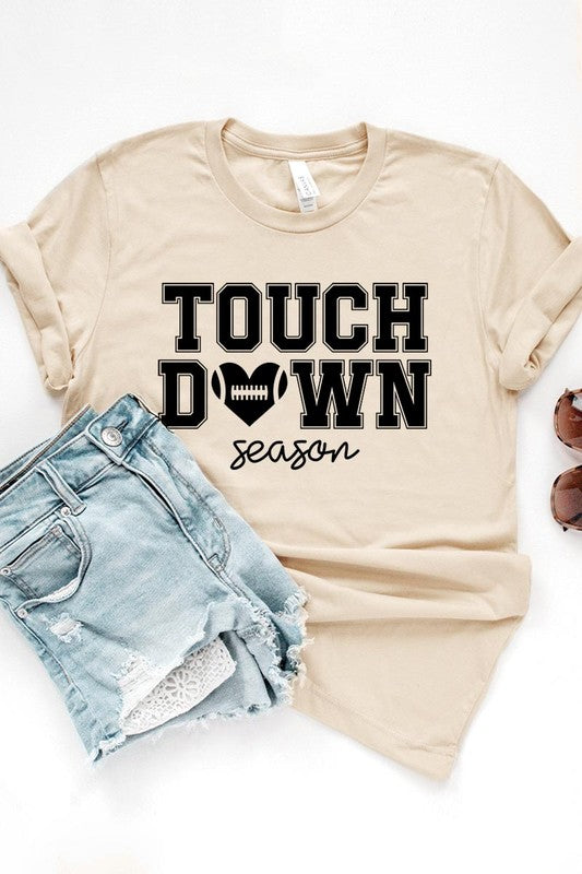 A Touchdown Season Graphic Tee in dark gray with a high-quality direct-to-film printed design, paired with blue jeans and beige ankle boots, laid out flat.